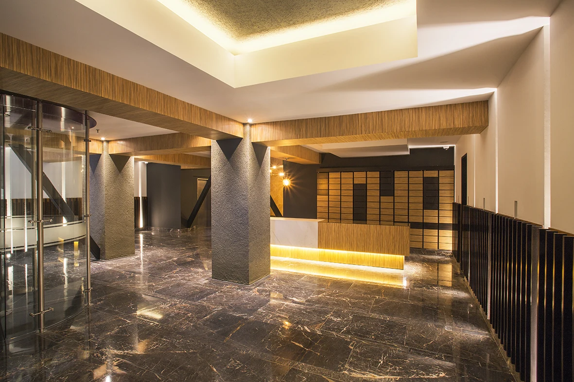 The lobby: timber and white stone reception under a stepped ceiling